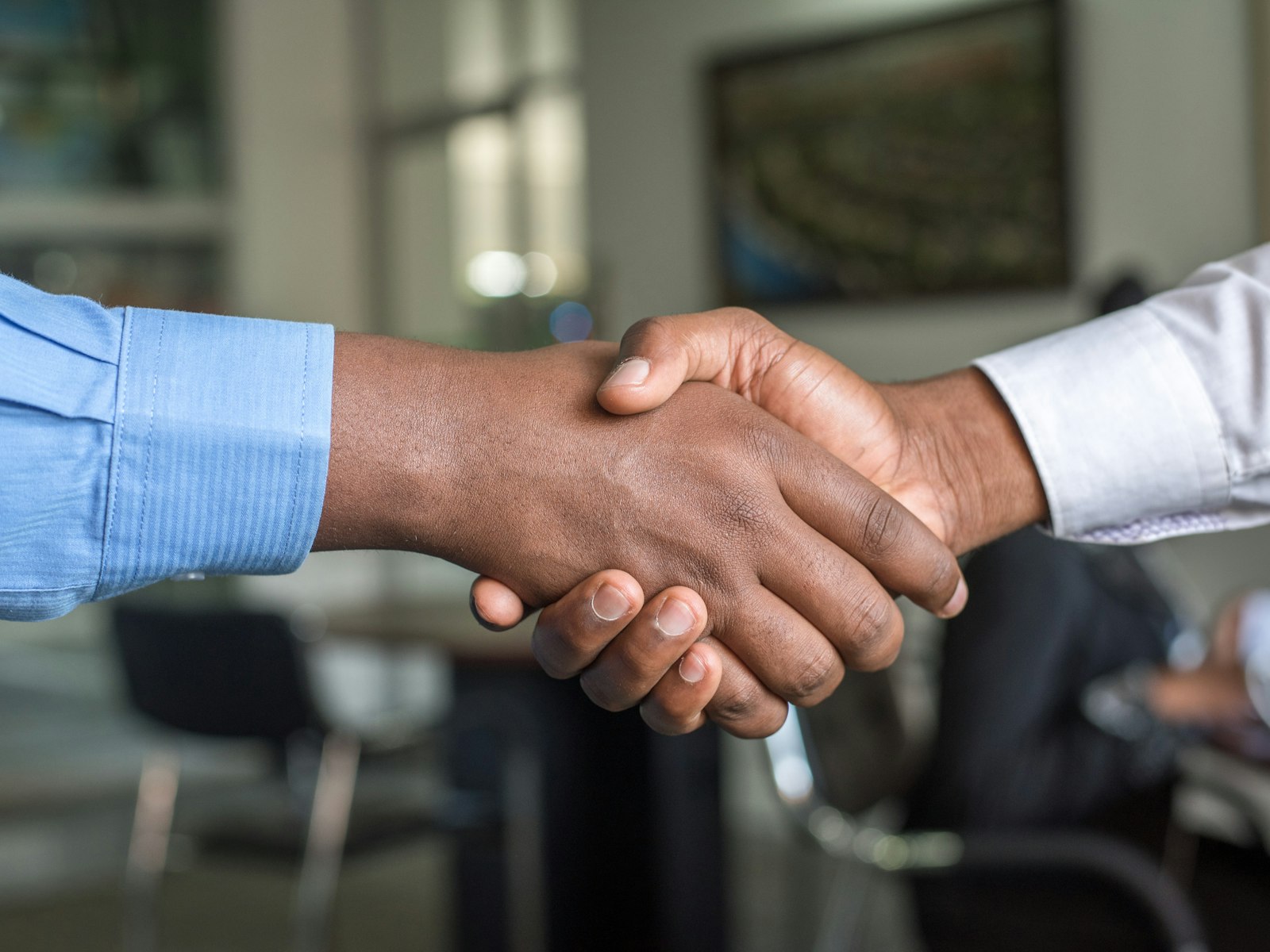 Two people shaking hands across a desk